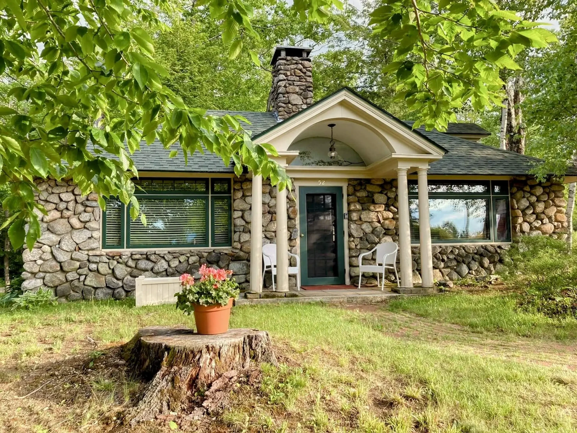 The stone cottage surrounded by leafy green trees