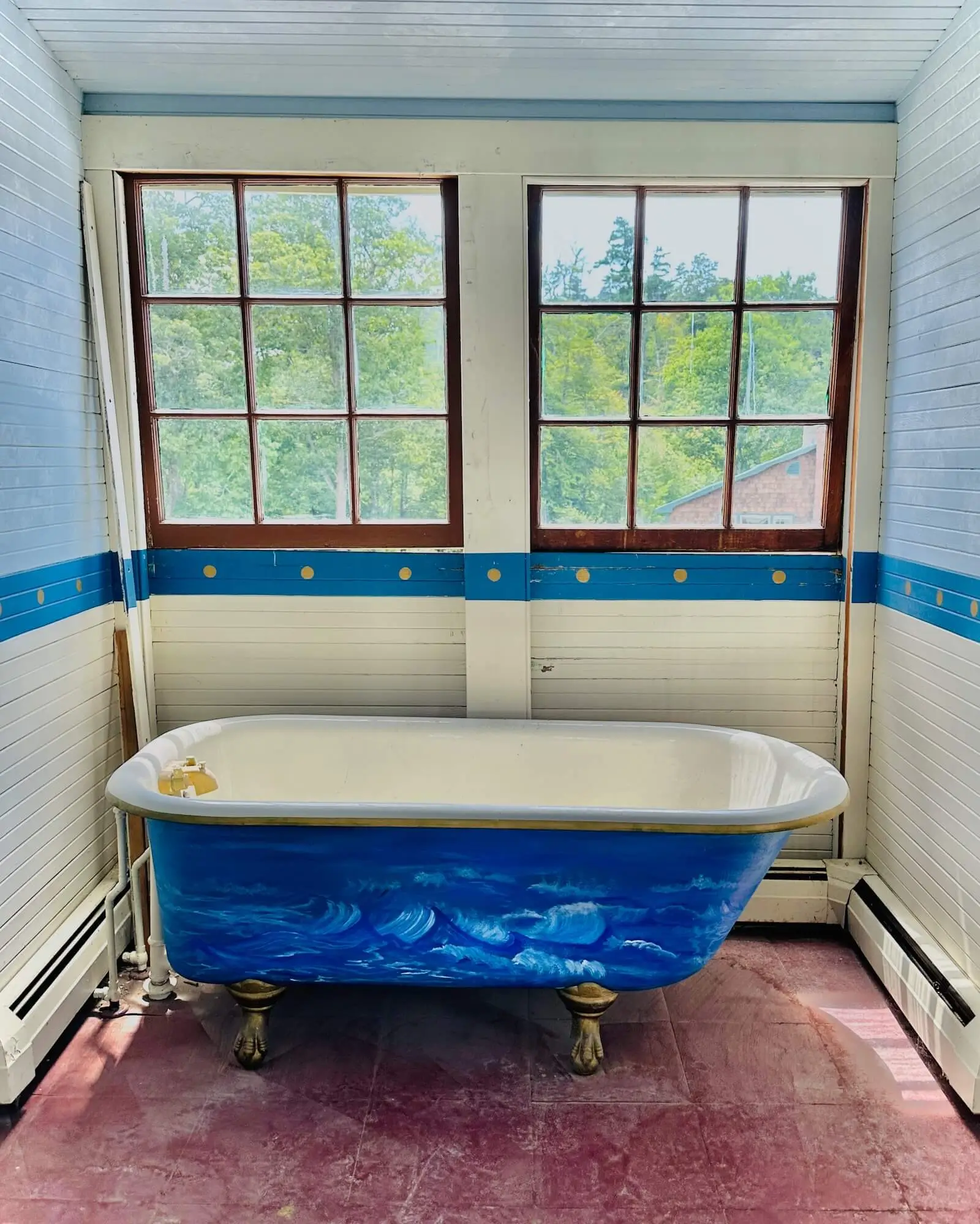 A vintage blue bathtub in a windowed room