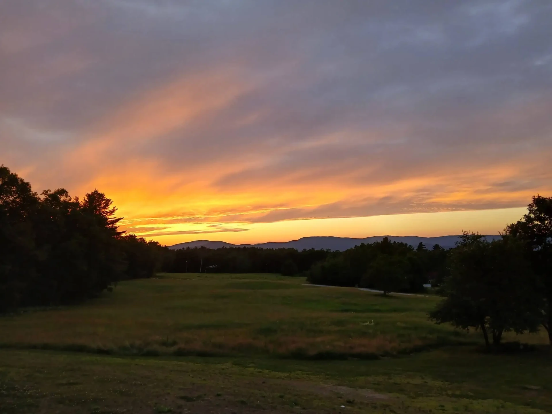 Sunset over a field and distant mountains